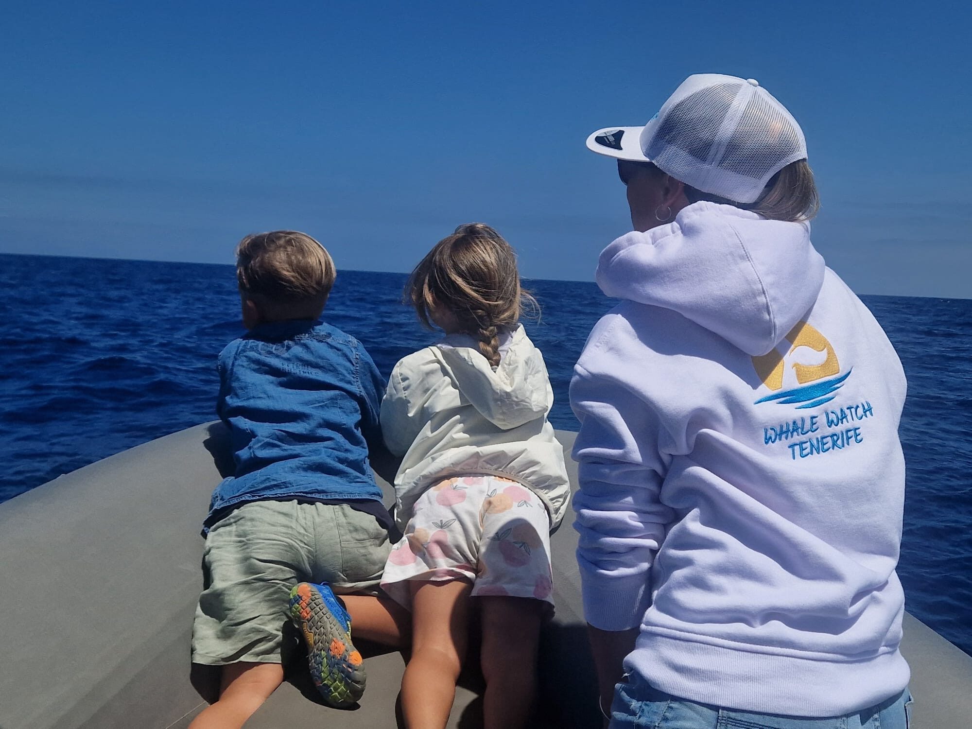 Two children watching for dolphins from a small whale watching boat in Tenerife